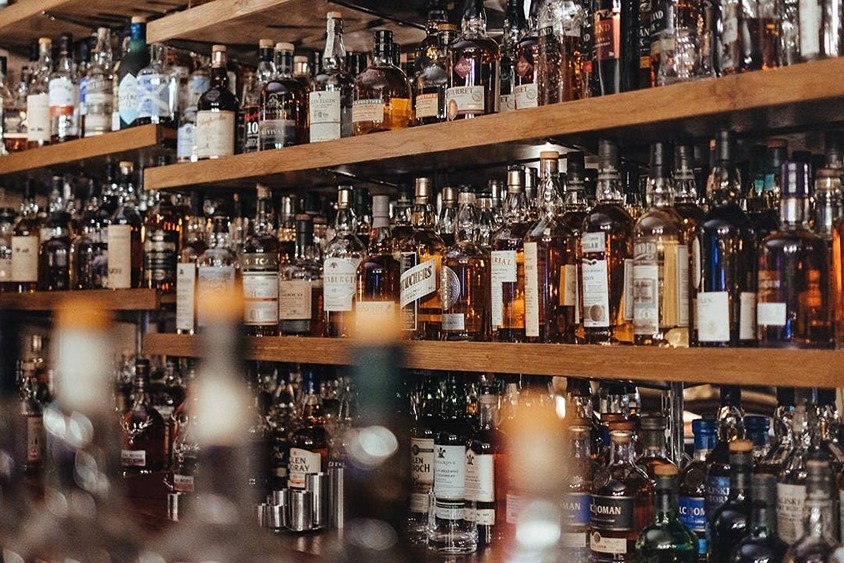 A shelf full of alcoholic drinks.